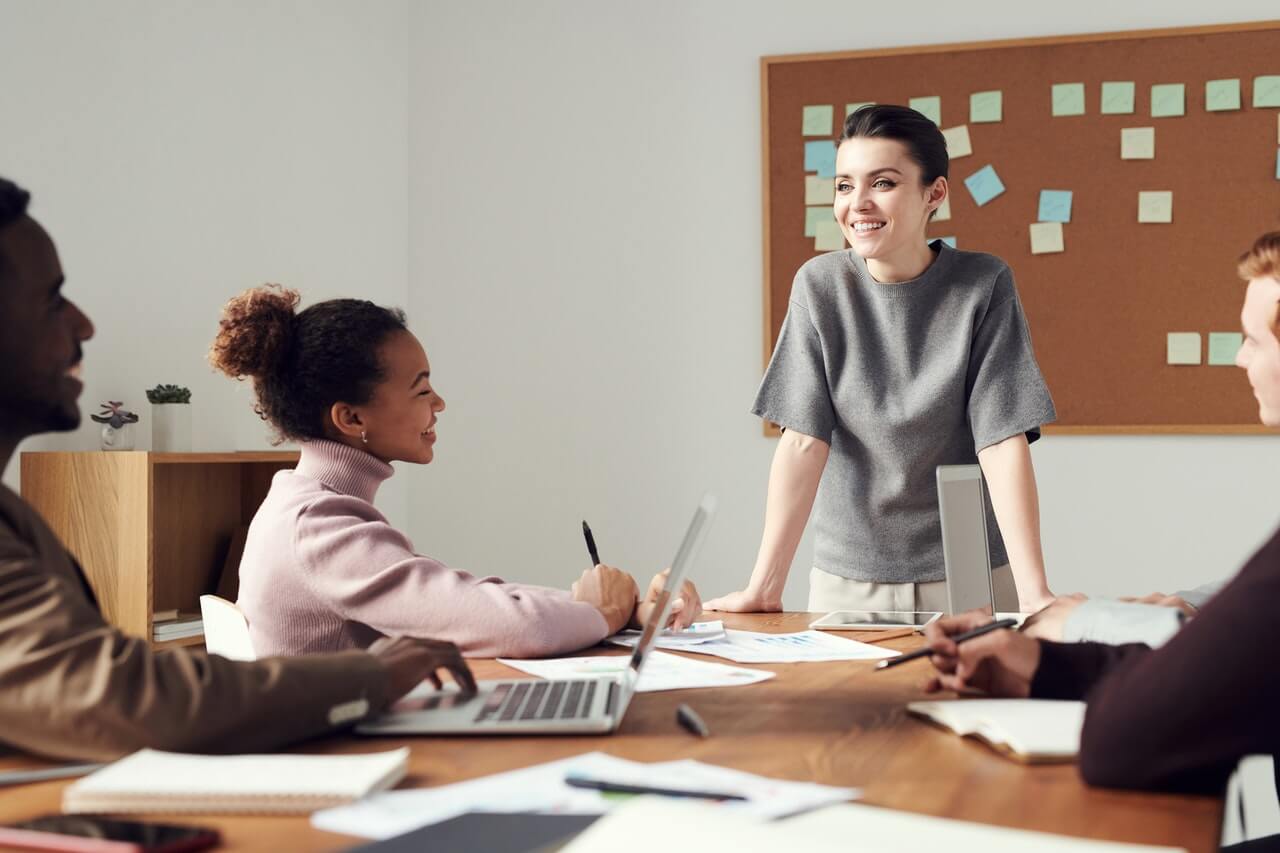 Woman standing in front of her team members smiling