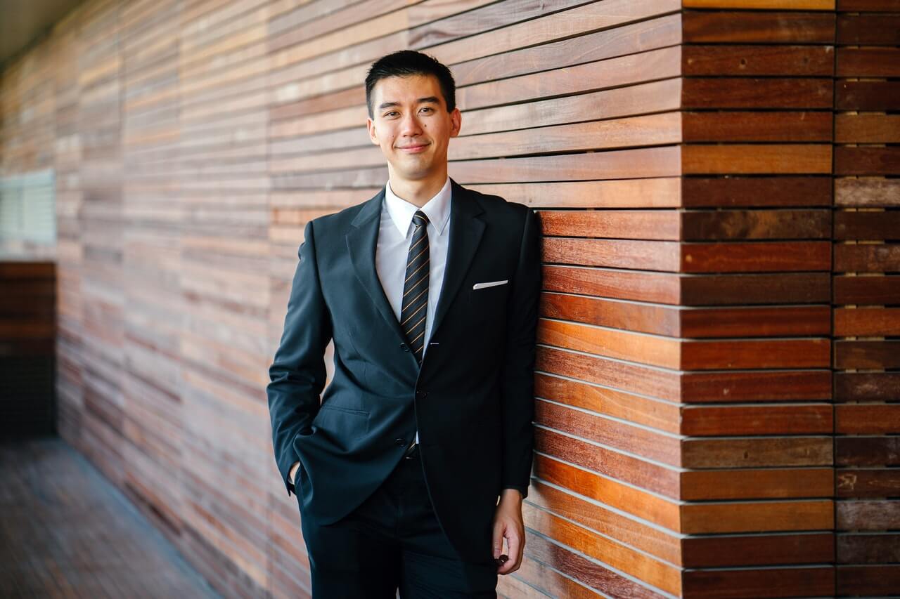 Man in suit leaning on a wall