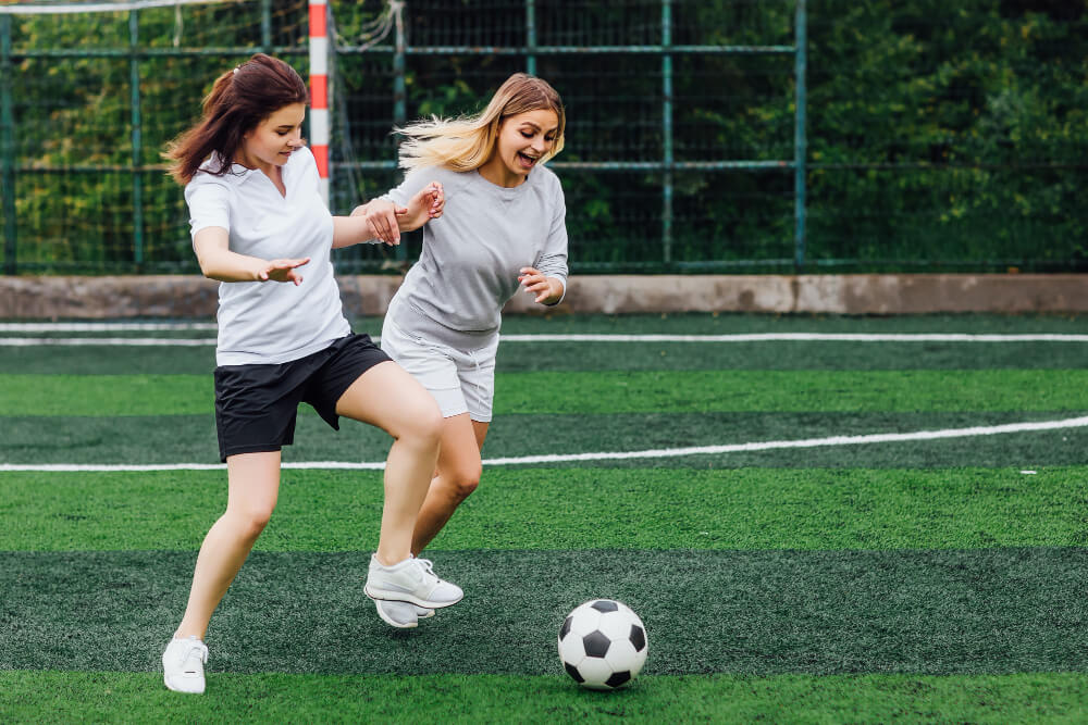 Two female soccer players playing on the field