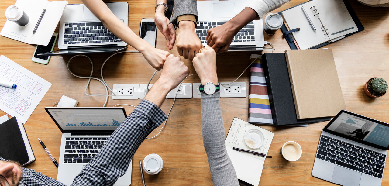 Work colleagues fist bumping each other at work