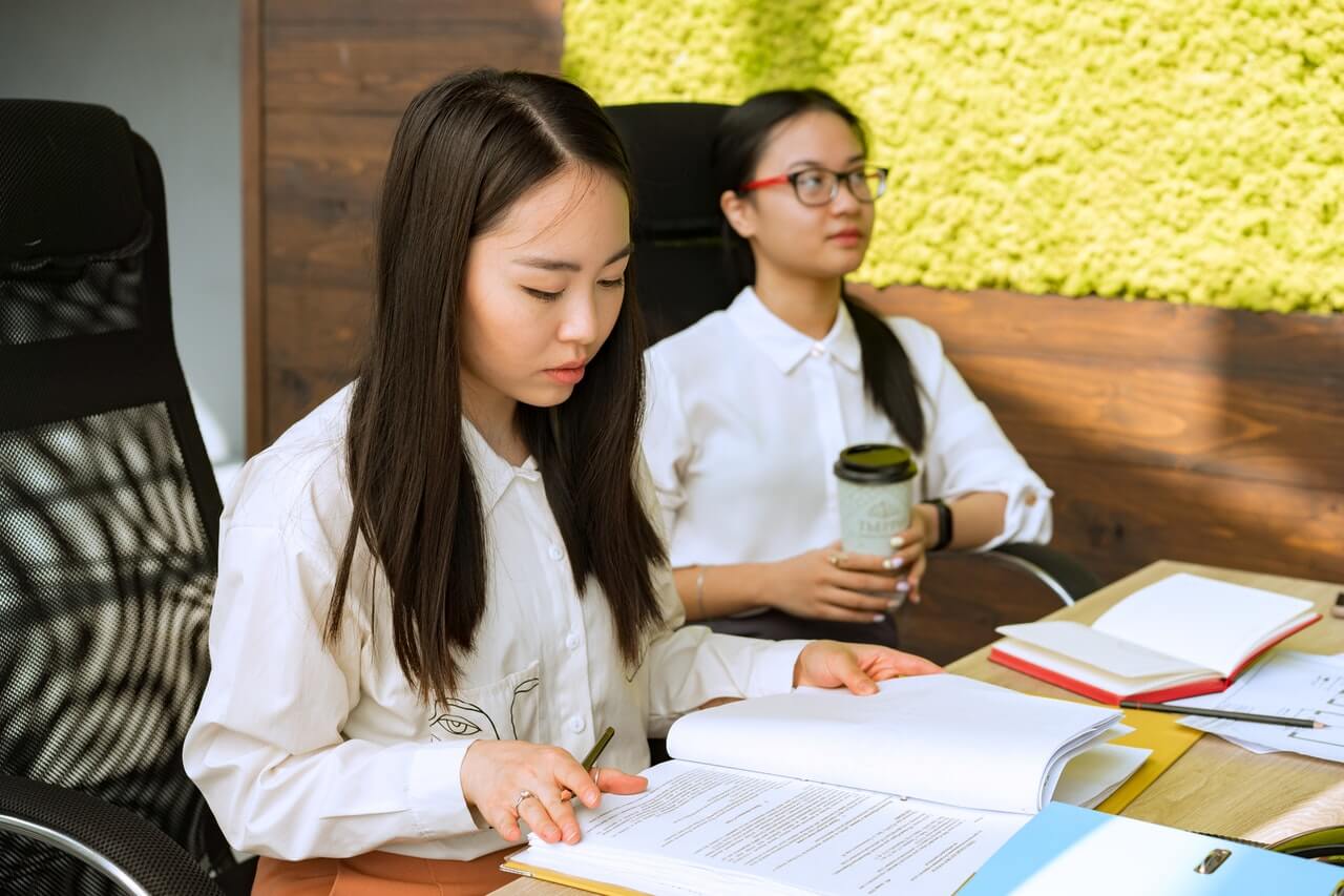 Woman beside a colleague going through business files