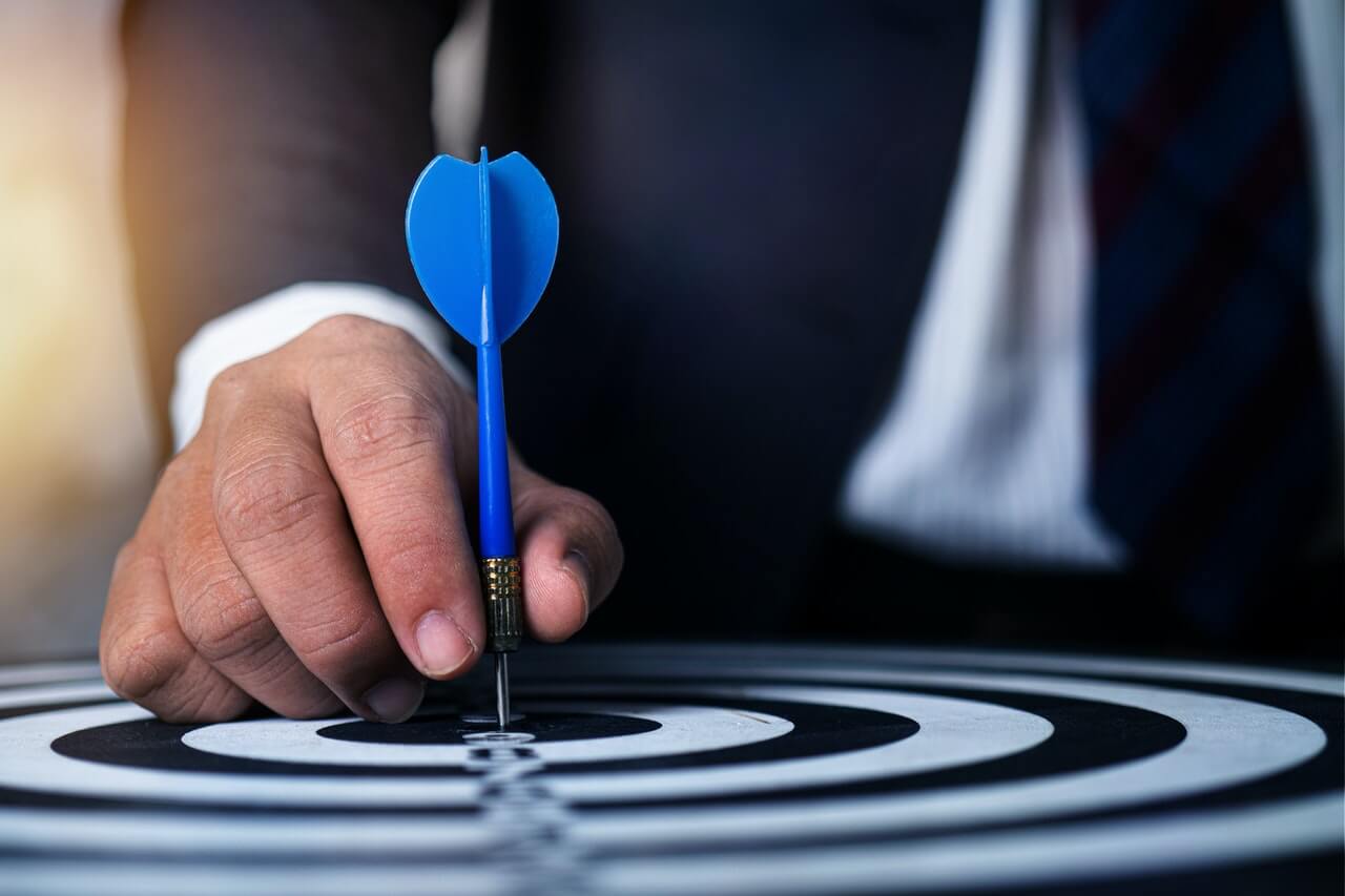 Man in suit pinning a blue dart pin to the board