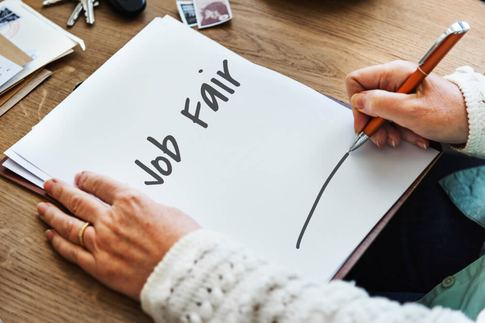 Person writing job fair in a note