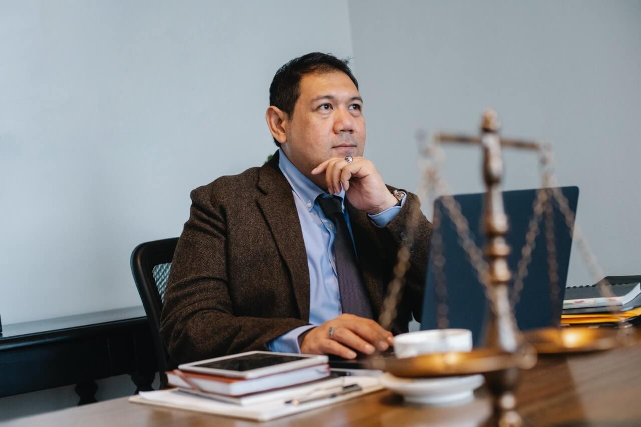 Man wearing suit in an office with a weighing scale on the table