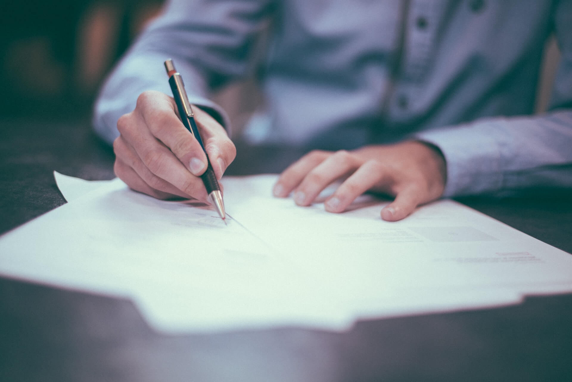 Man in blue shirt signing a business contract