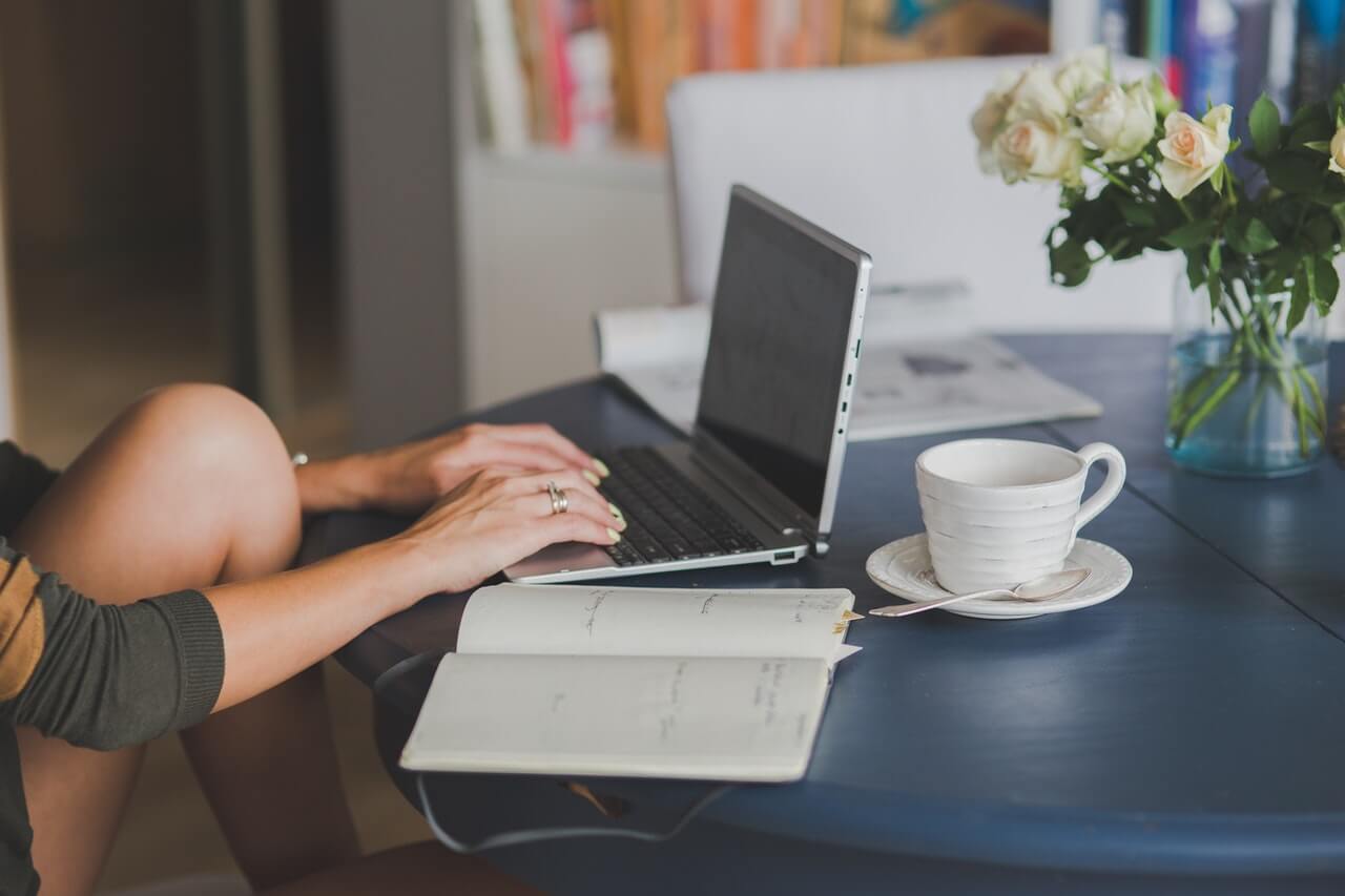 Person using a laptop and a note