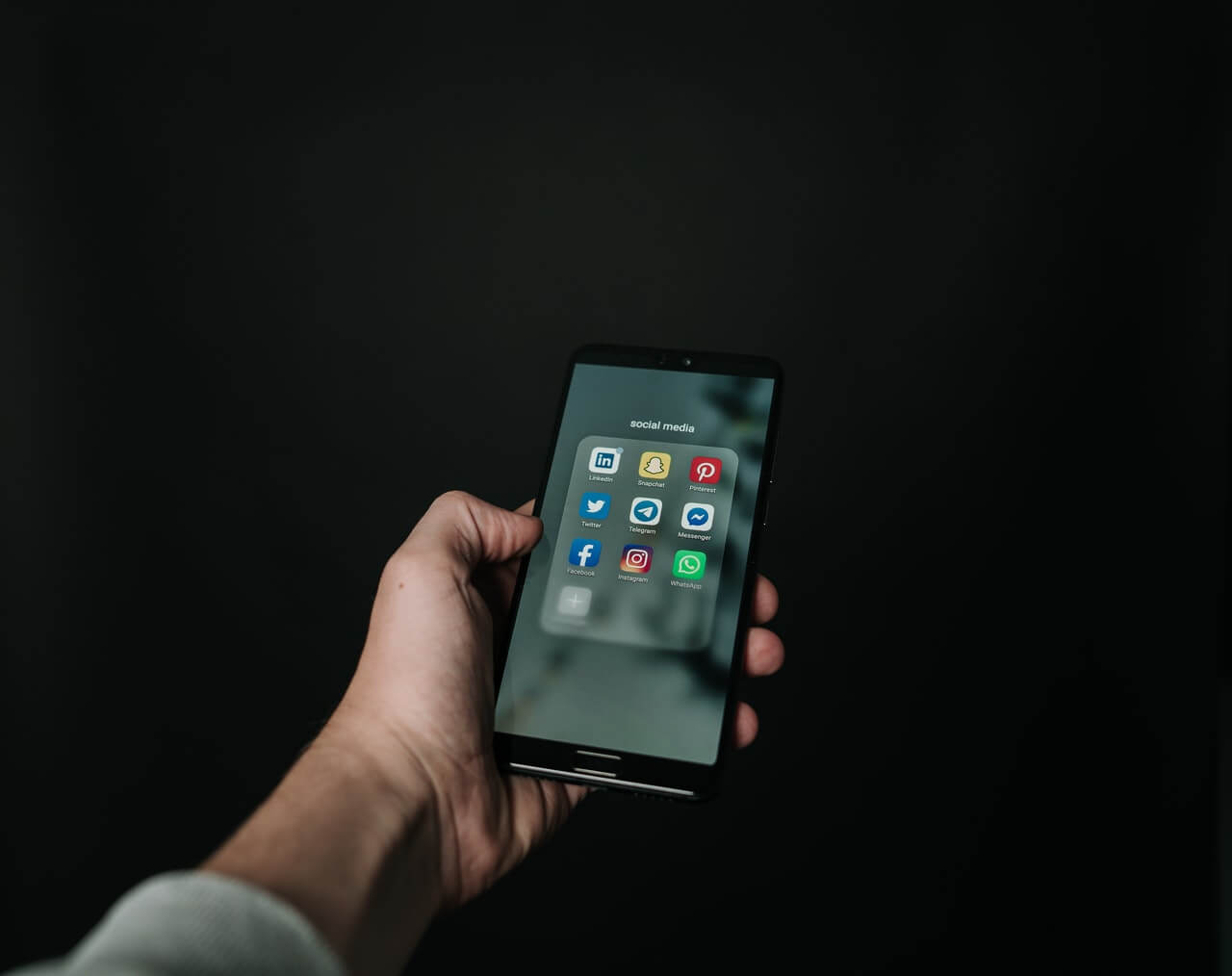 Hand holding a phone showing the different social networks on its screen