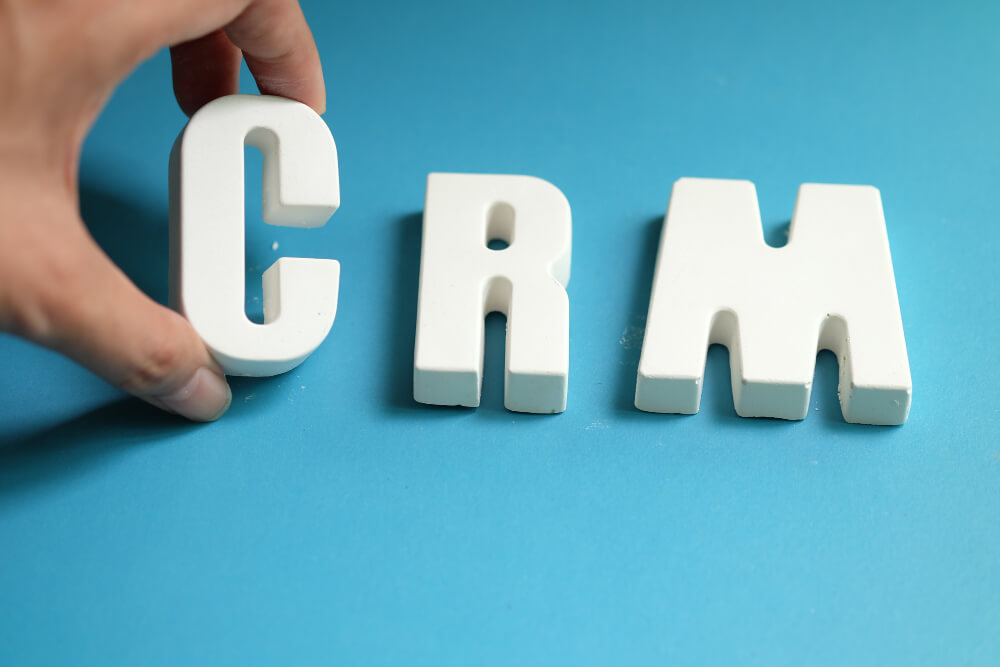 Hand arranging white letters to spell CRM