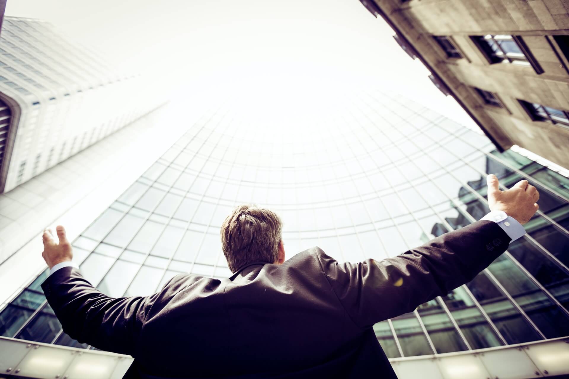 A businessman looking up at a corporate building