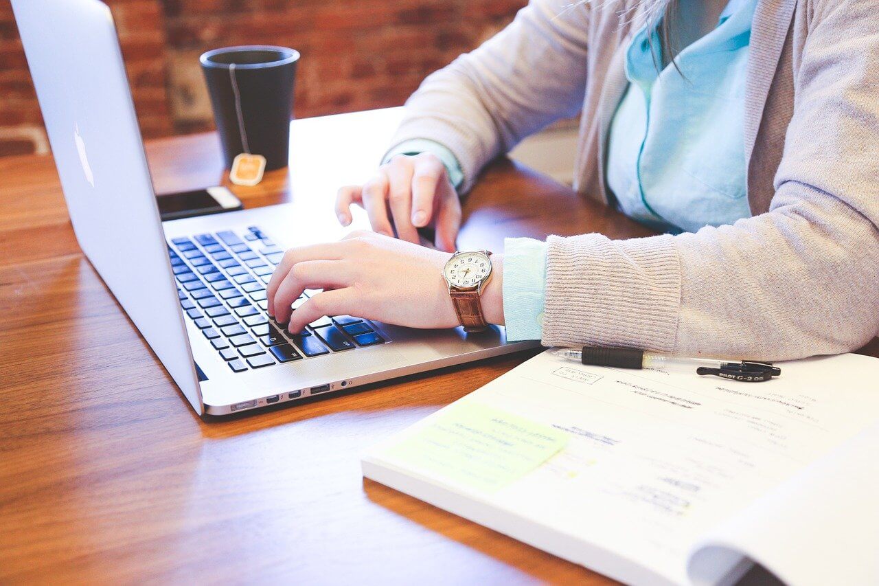 Someone typing a business report with a laptop