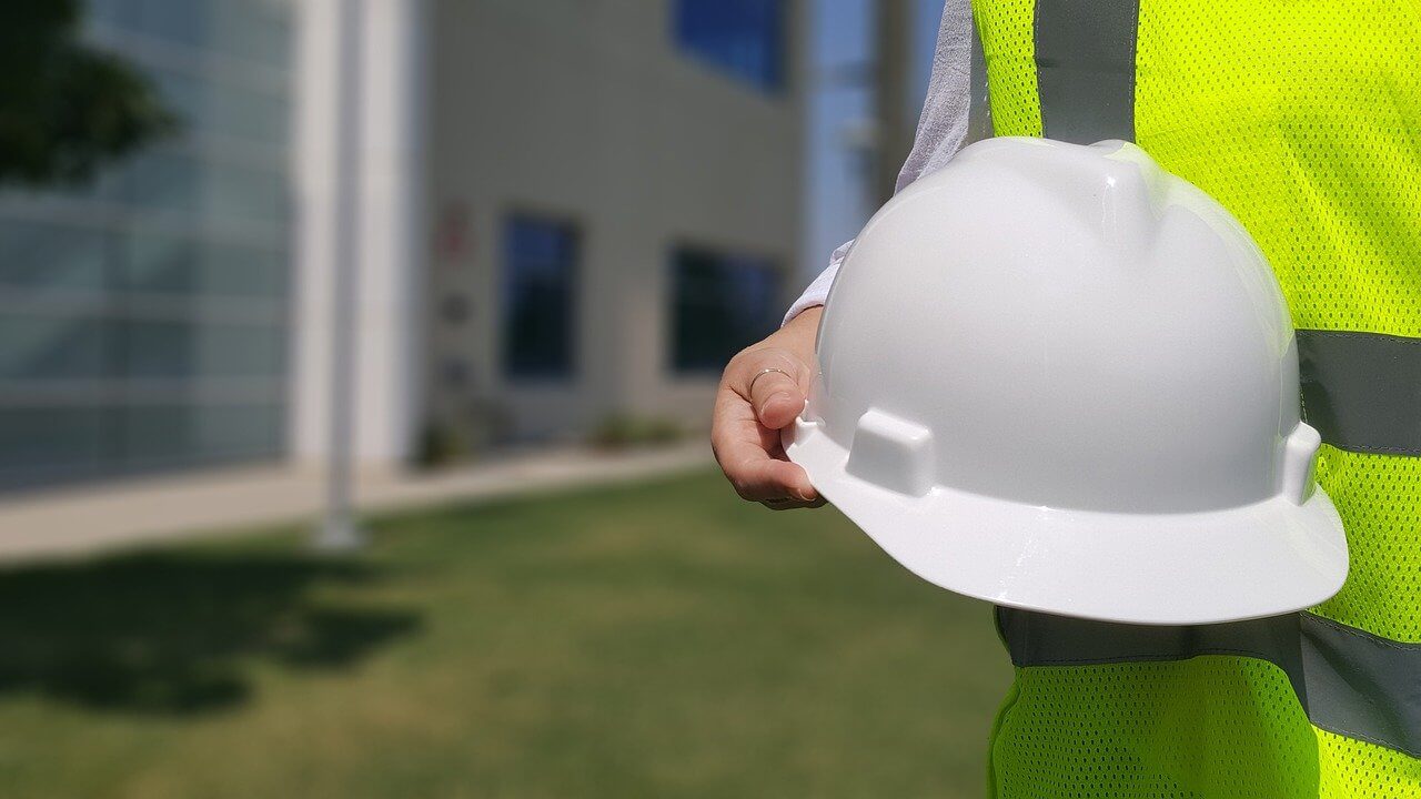 Person in green vest holding an helmet