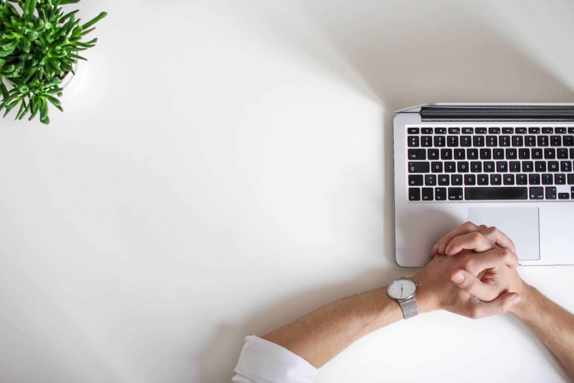 Hands resting on a laptop on a white desk