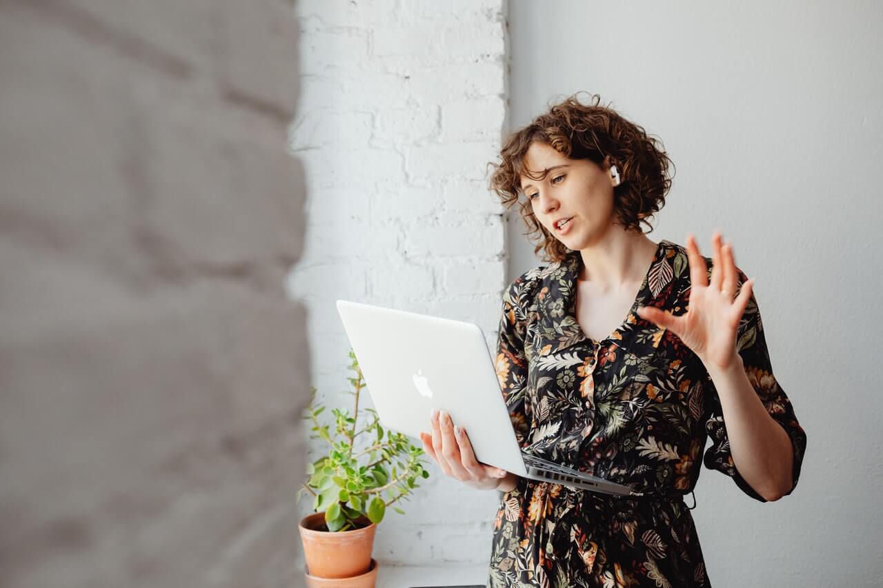 Young woman in a floral dress holding a laptop