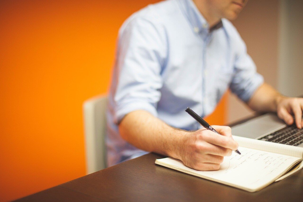 Someone writing a grant proposal on an office desk