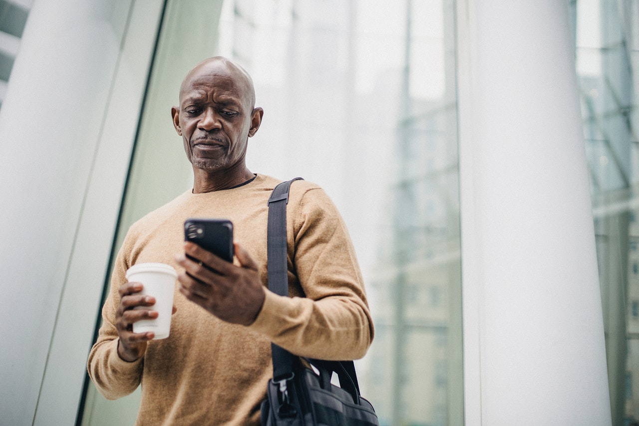 A-man-holding-a-coffee-and-pressing-his-phone