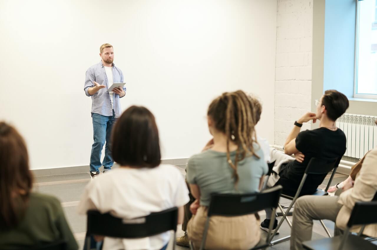 A-person-wearing-blue-jeans-and-a-shirt-talking-to-a-group