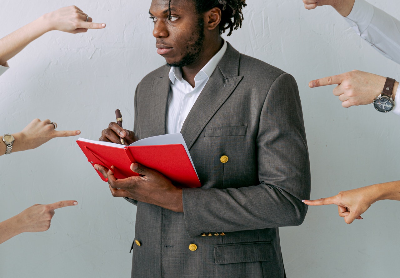 A-young-man-writing-with-hands-pointing-at-him