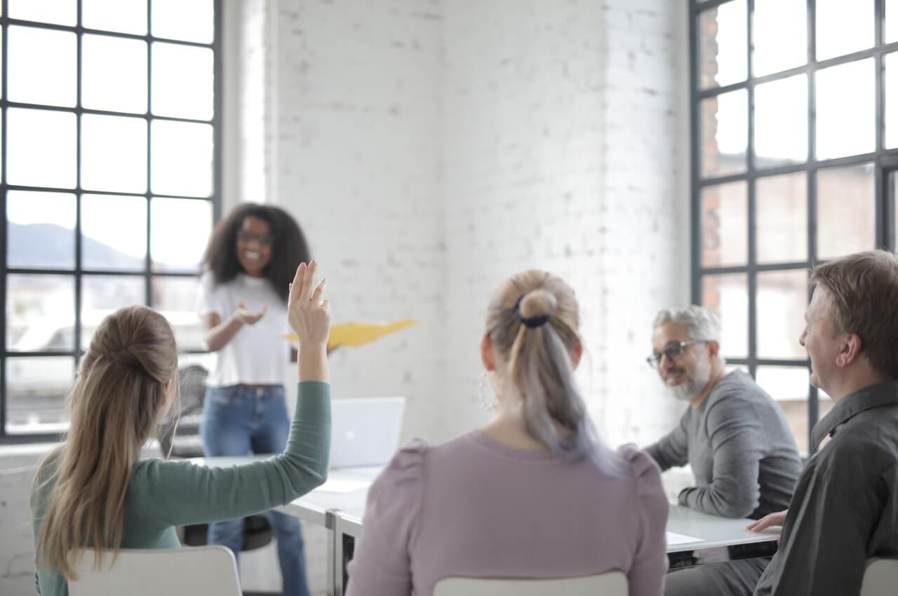 Female-employee-raising-her-hands-to-ask-question-in-a-conference-hall