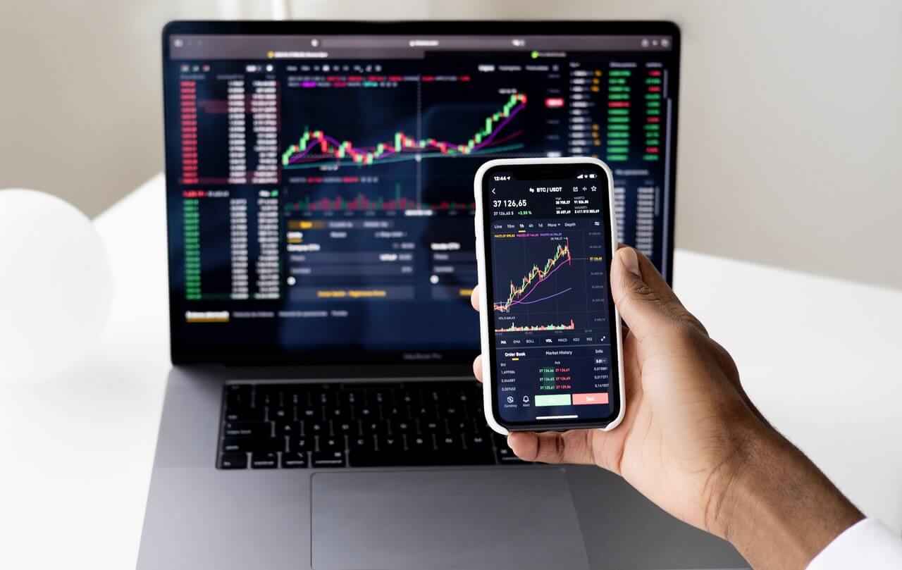 Someone learning how to trade crypto with a laptop and phone