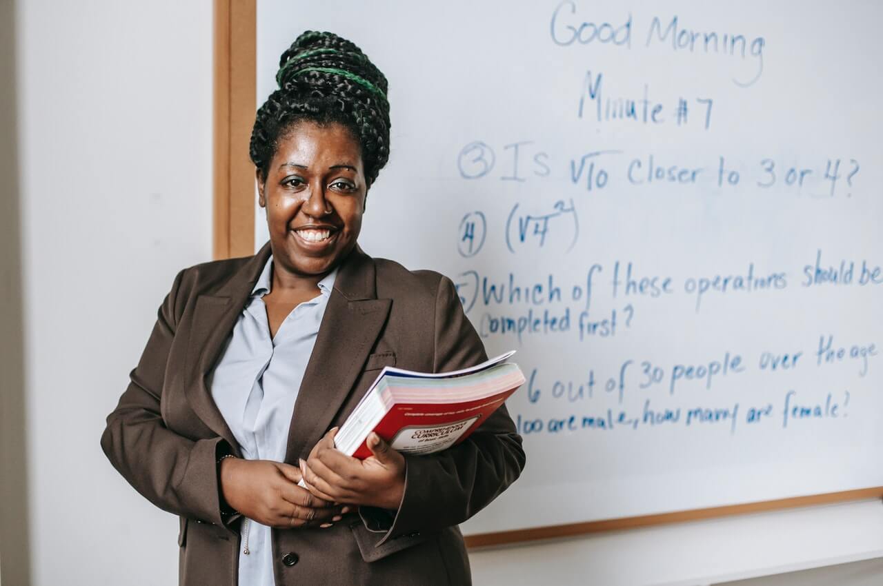 Teacher-smiling-behind-a-whiteboard.