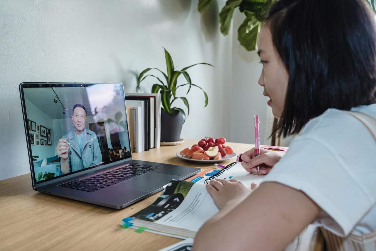 A-girl-watching-an-online-lecture-talk-from-a-man-on-her-laptop.