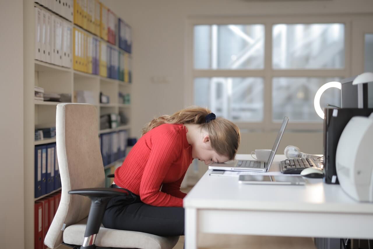 A-woman-placing-her-head-on-her-laptop