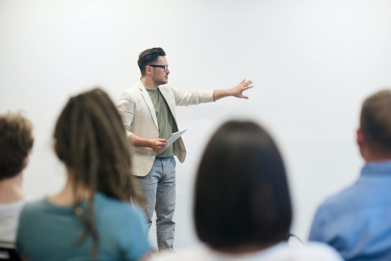 A young man having a professional presentation while pointing to the white board