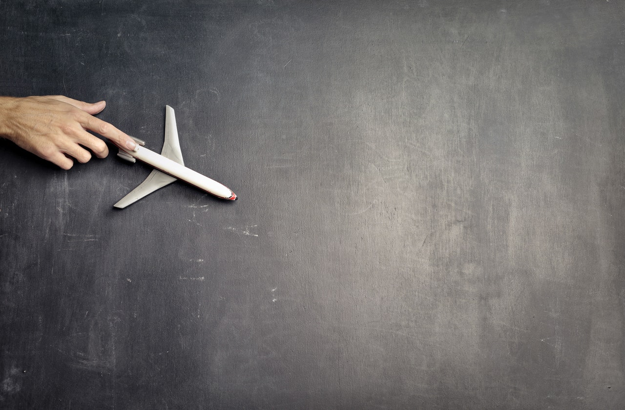 Anonymous person with miniature airplane on chalkboard