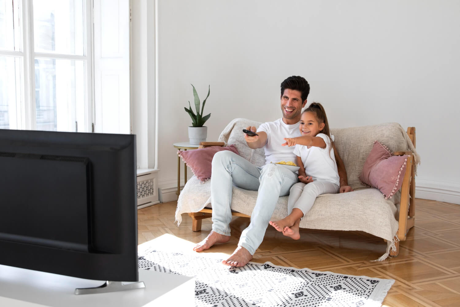 Dad and daughter watching ads on tv while laughing