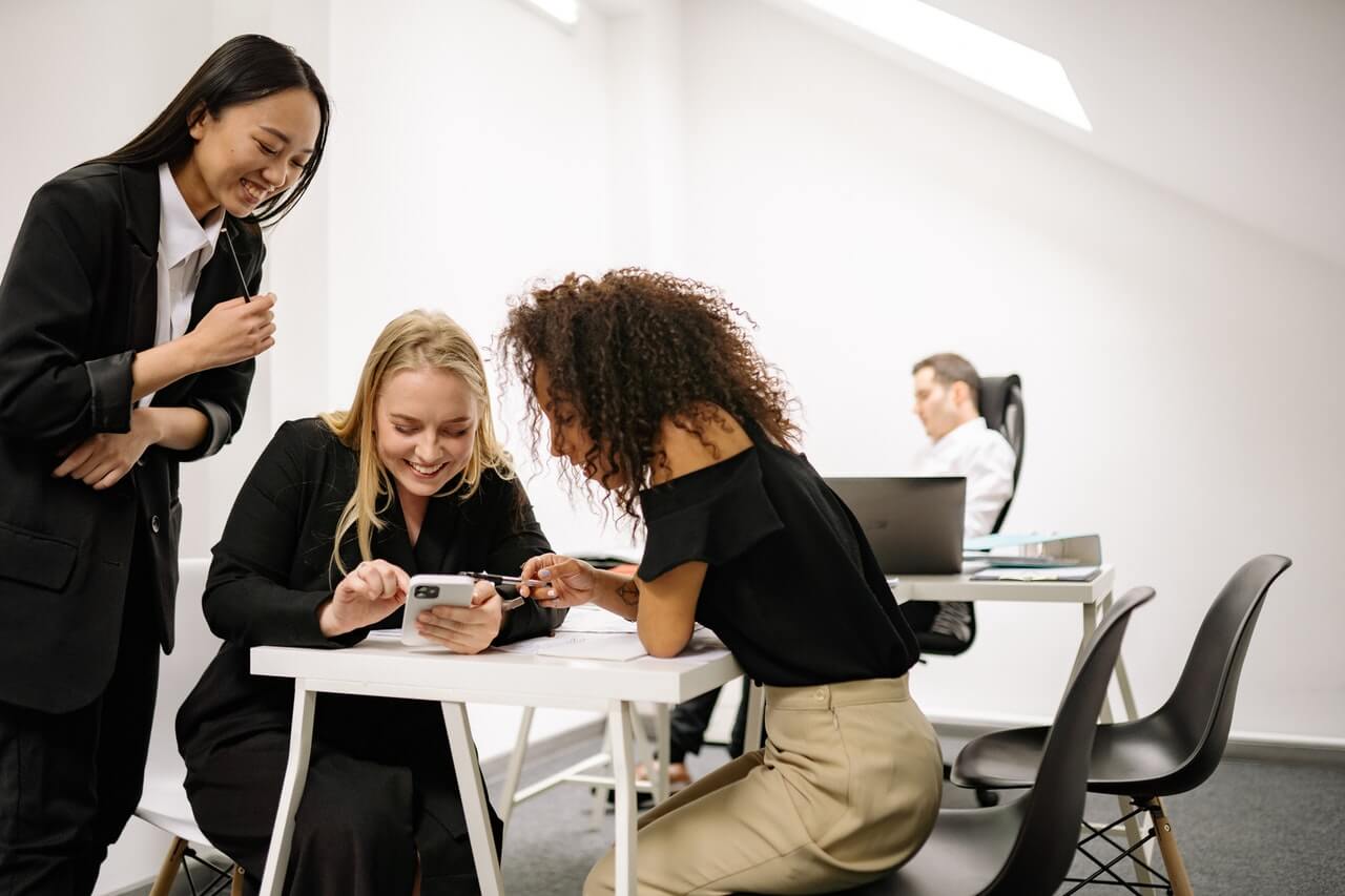 Female-colleagues-looking-at-a-post-in-a-phone-on-social-media