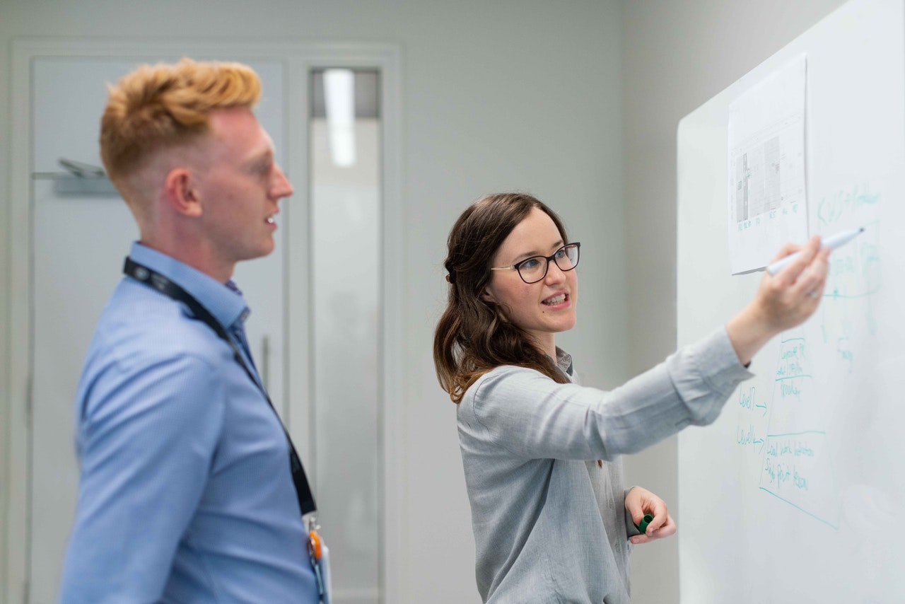 Young lady presenting while writing on the board