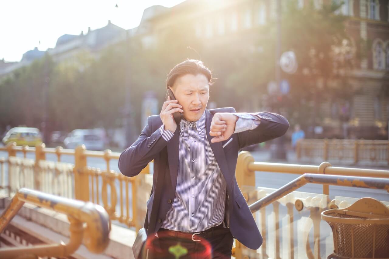 Man checking the time while walking and making a phone call