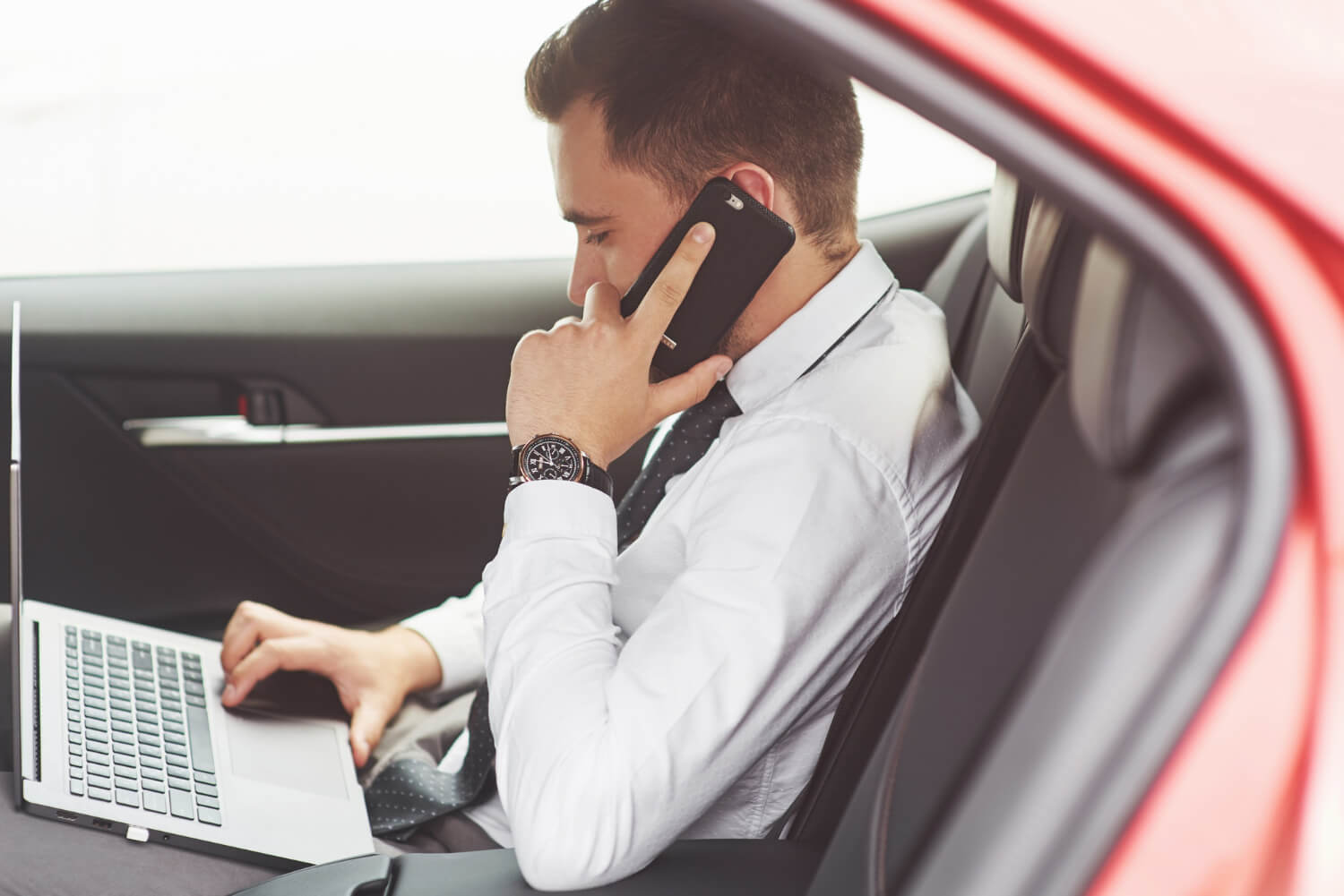 Man working on laptop while testing on mobile device