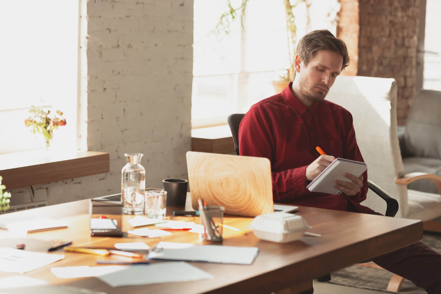 Man trying to write in a disorganized office space