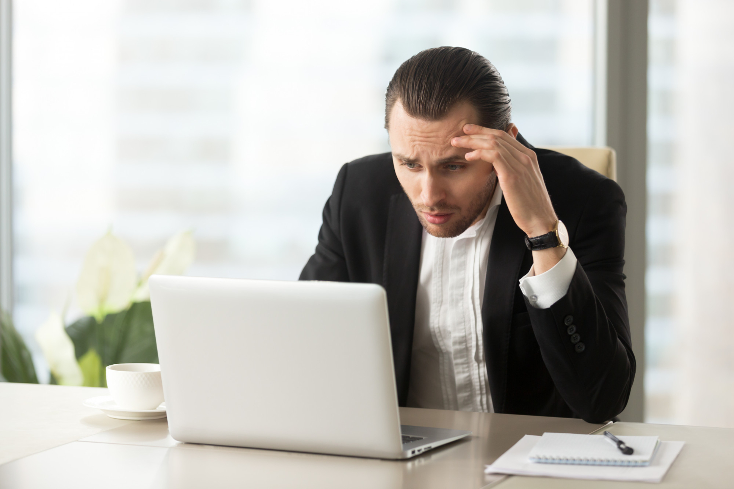 Business man going through crisis looking at his laptop