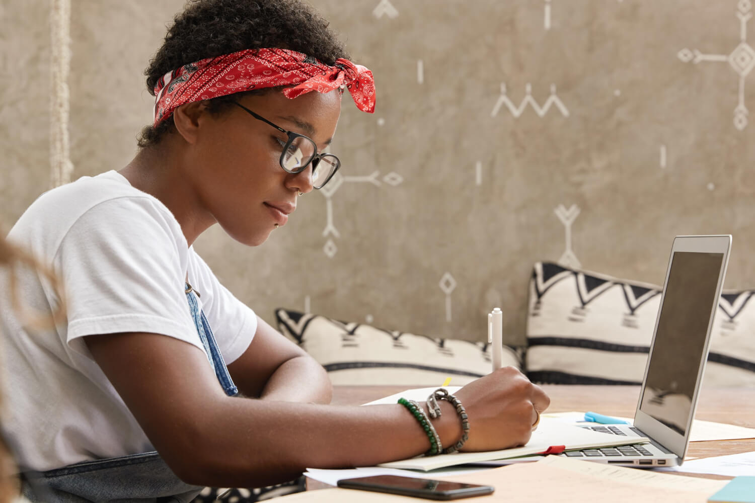 A young woman working while taking down notes