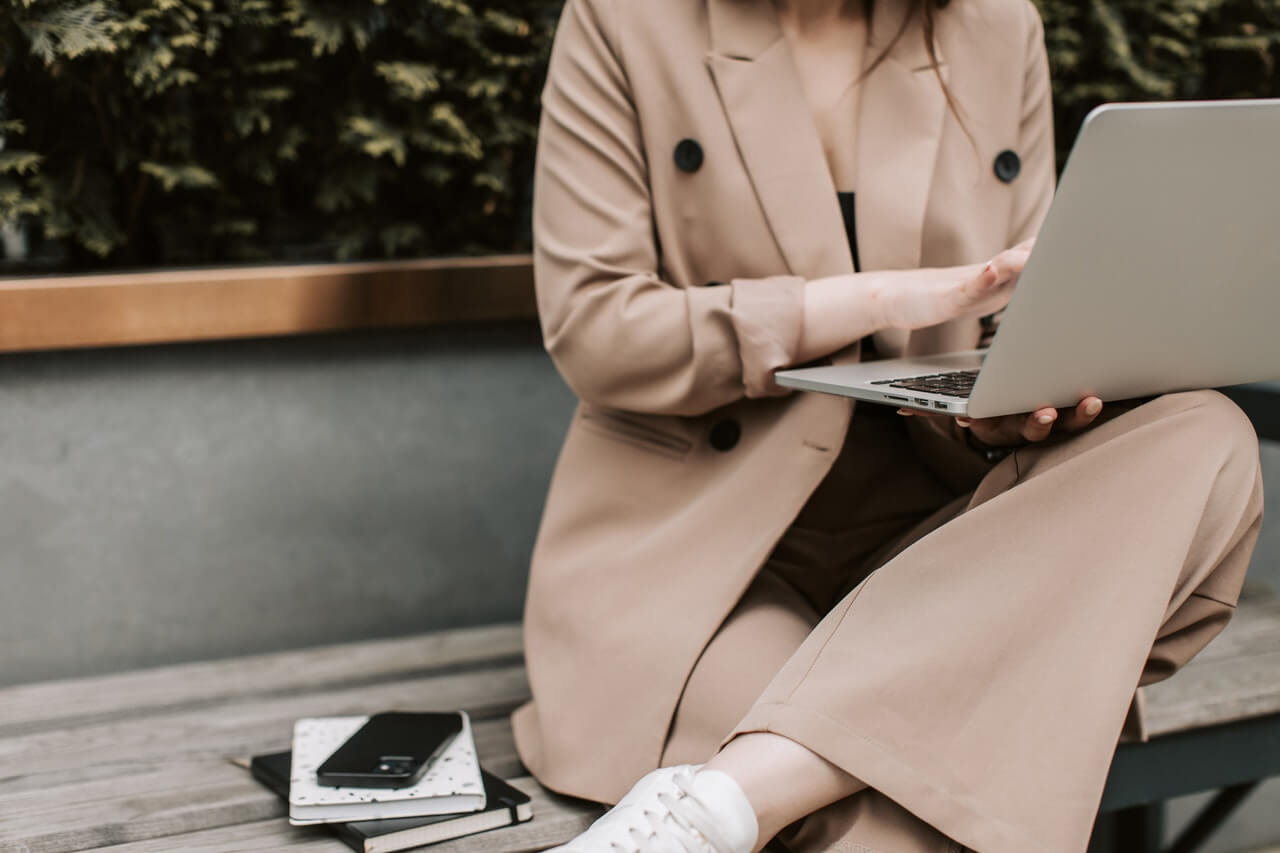 A Person in a Suit Sitting on the Bench while Using a Laptop