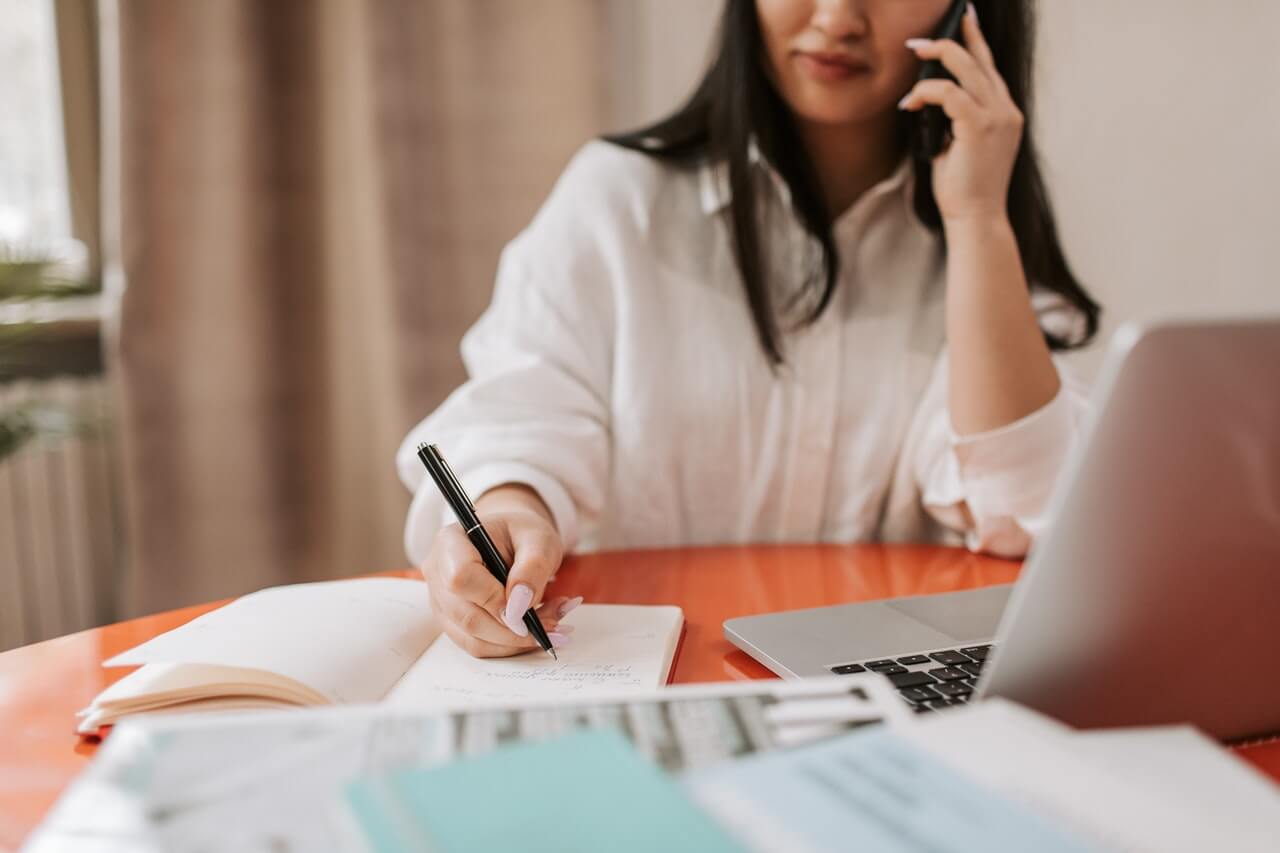 A-businesswoman-on-call-and-writing-out-notes-for-her-staffs