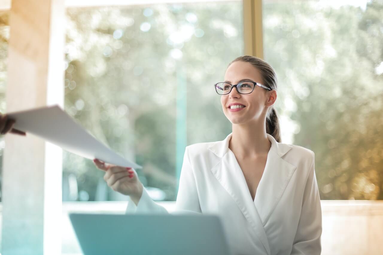 A-lady-smiling-while-passing-a-file-in-her-office.