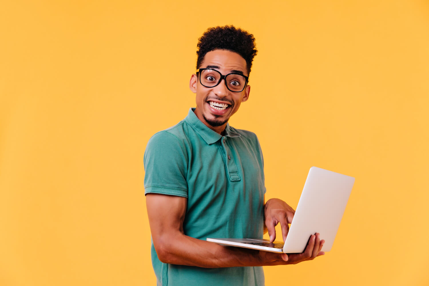 Young male freelancer smiling while holding a laptop