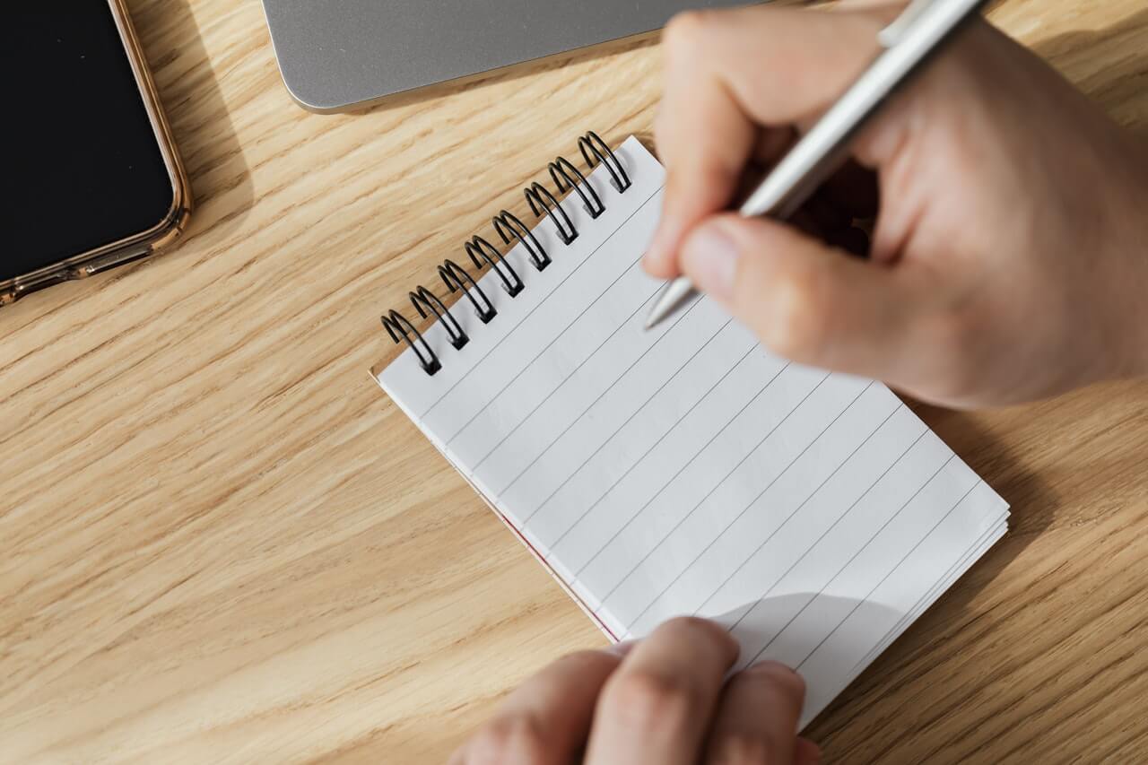 Crop man with pen and opened notebook