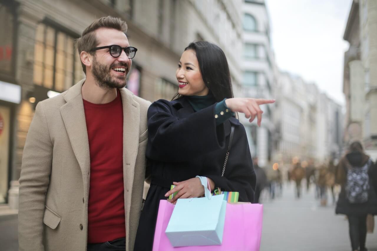 Joyful couples pointing to a shop after shopping with them