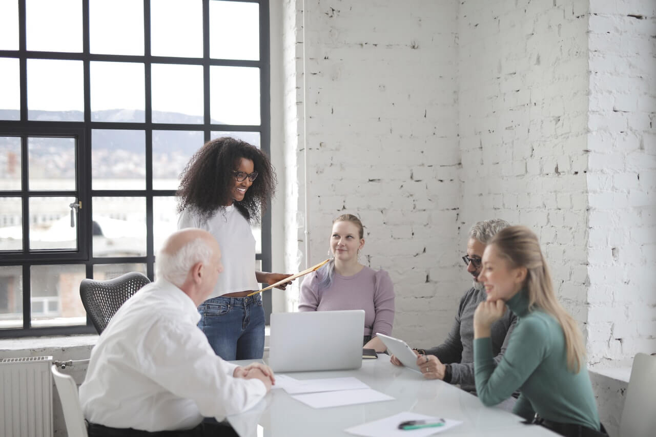 Lady on white top laughing presenting to her coworkers