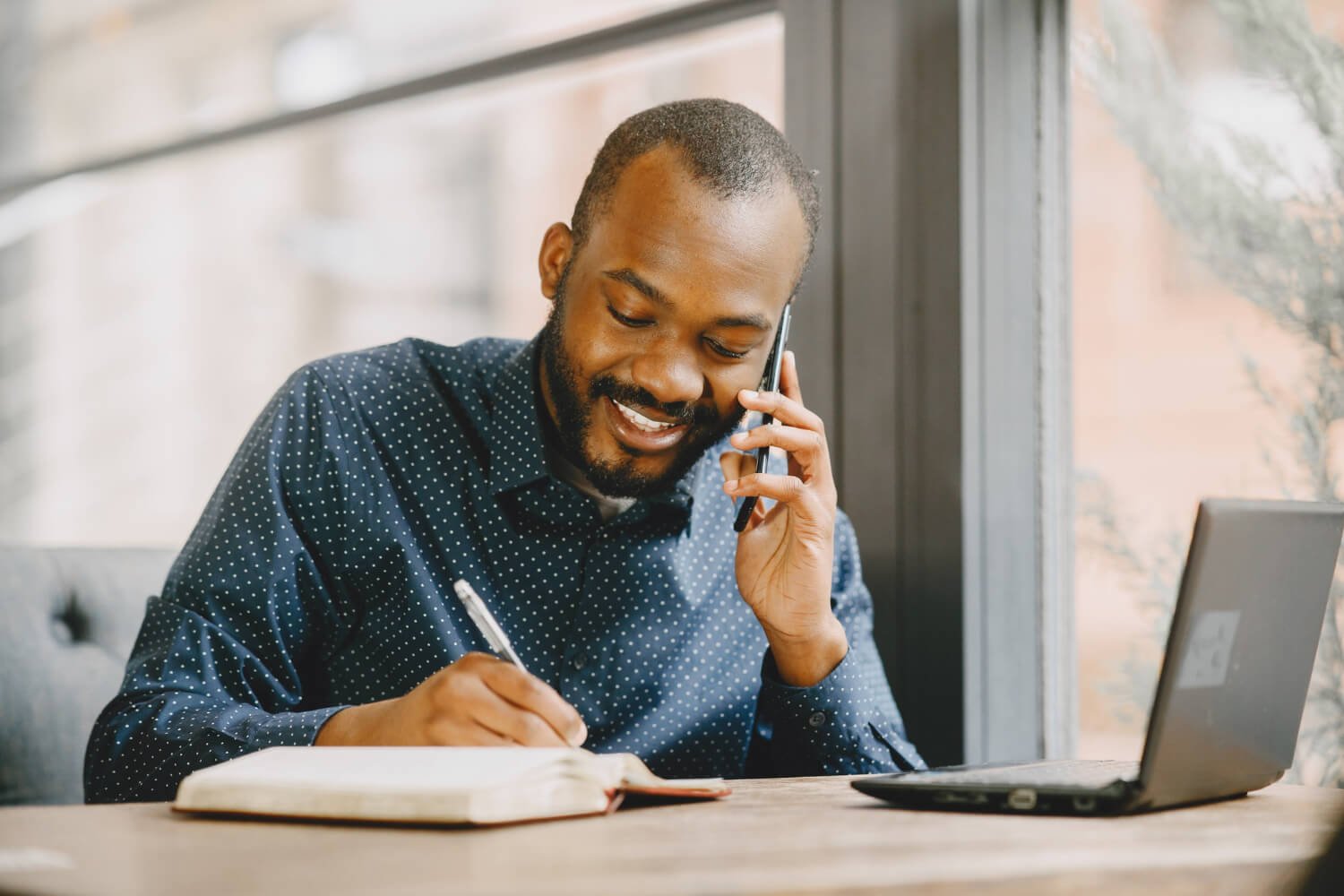 young man working on his laptop talking on a phone