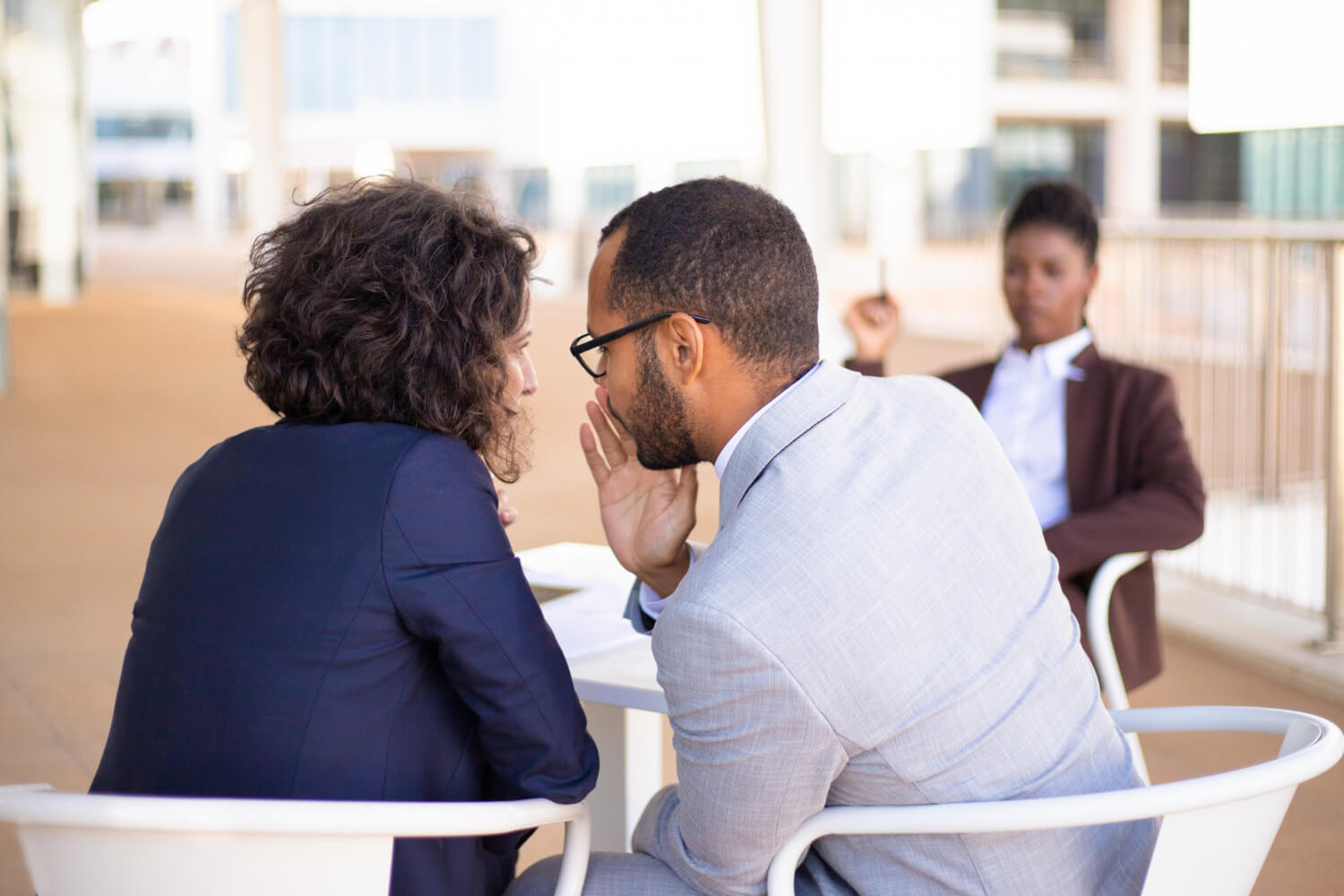 Young man whispering to his colleague