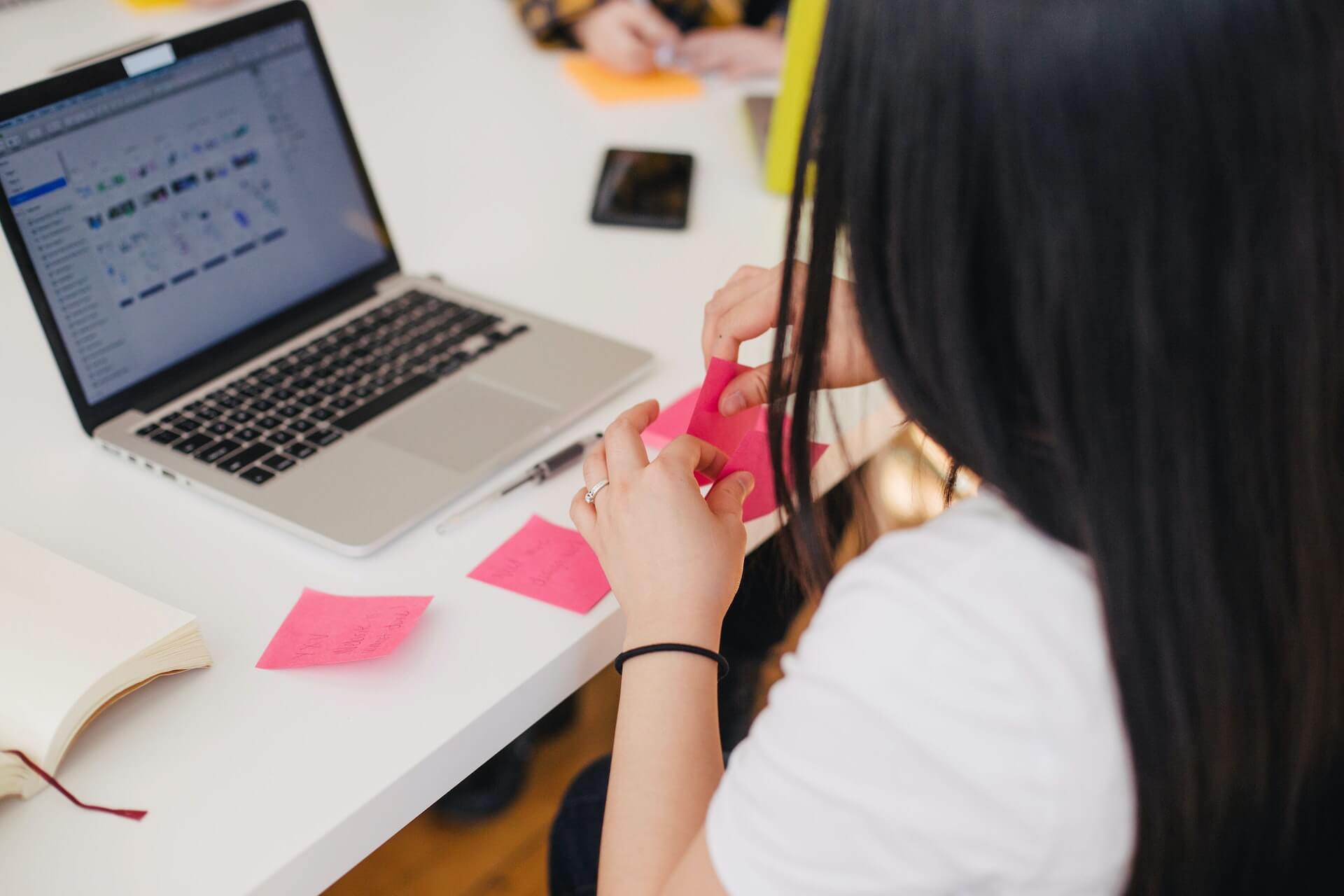 A lady holding a sticky note while working