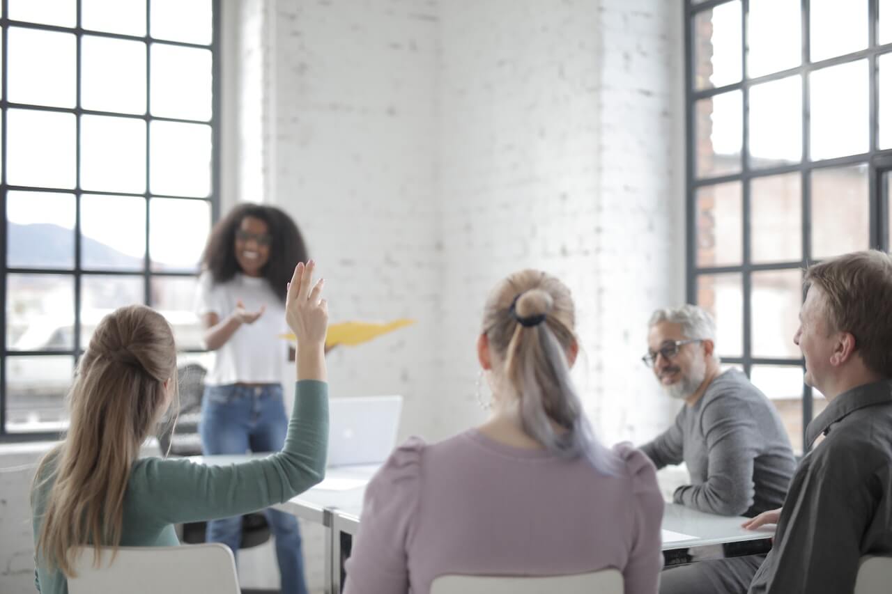 Employee raising hand for asking question at conference in office boardroom