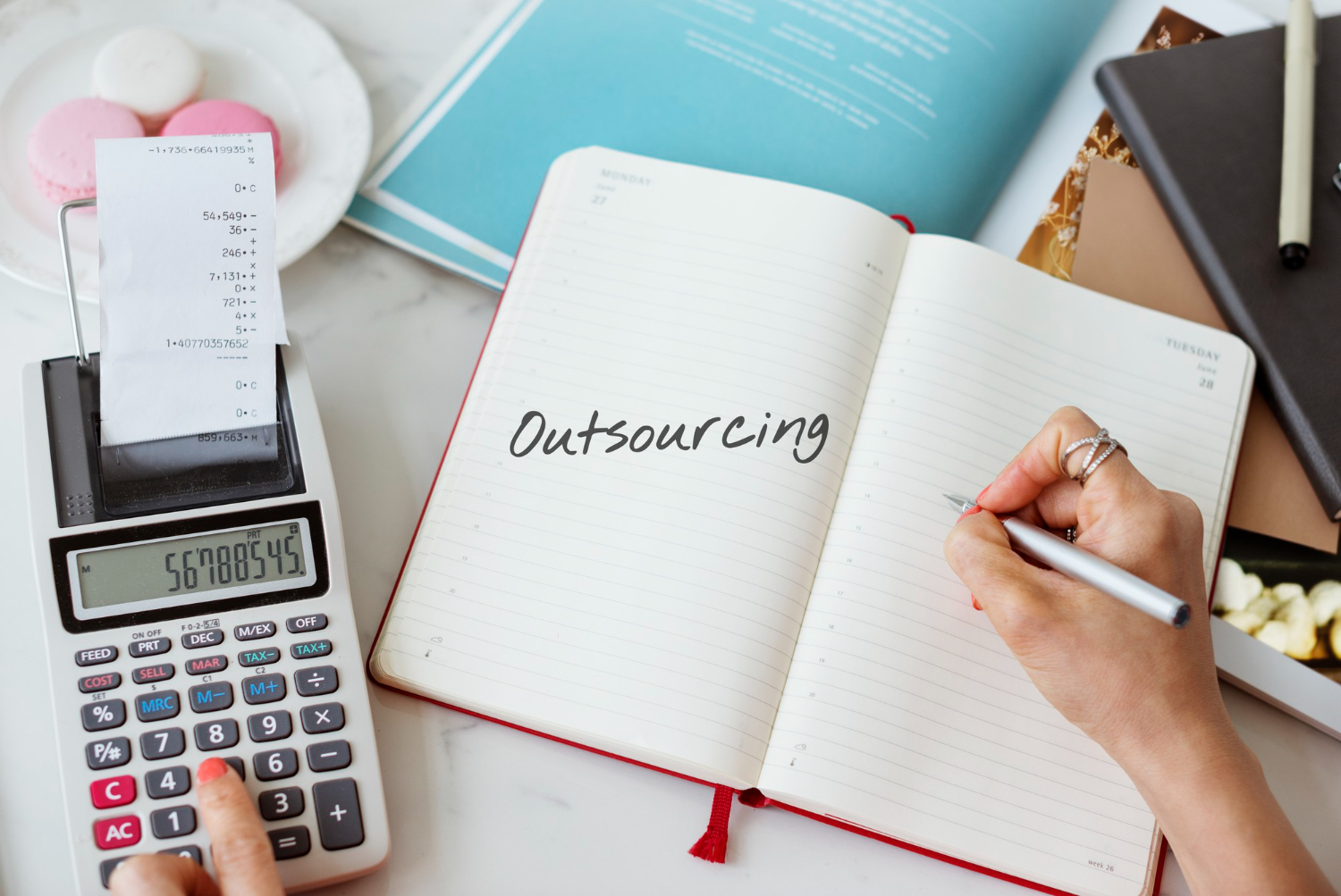 Lady holding a pen, outsourcing written on a notebook