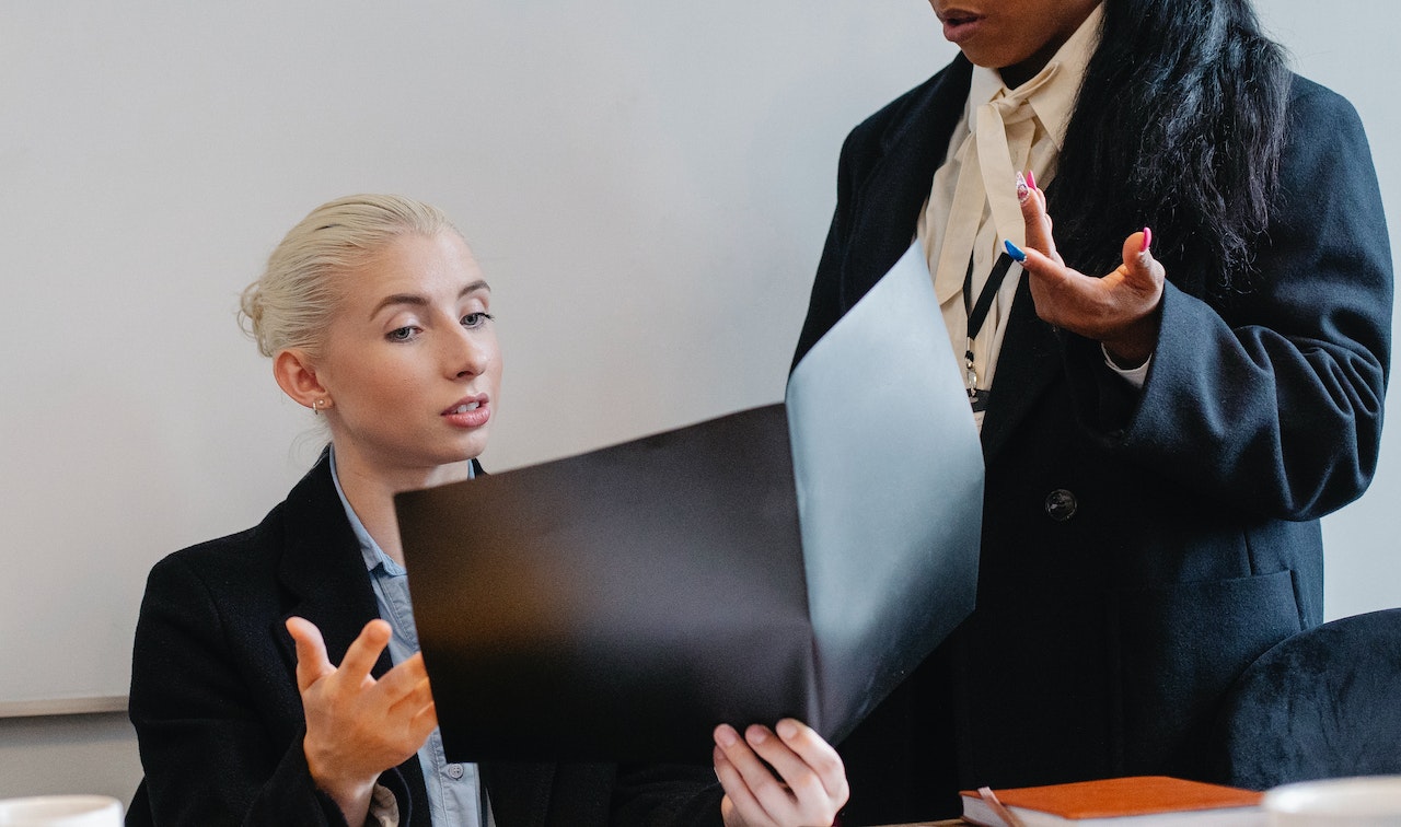 Young woman with black folder explaining to her supervisor