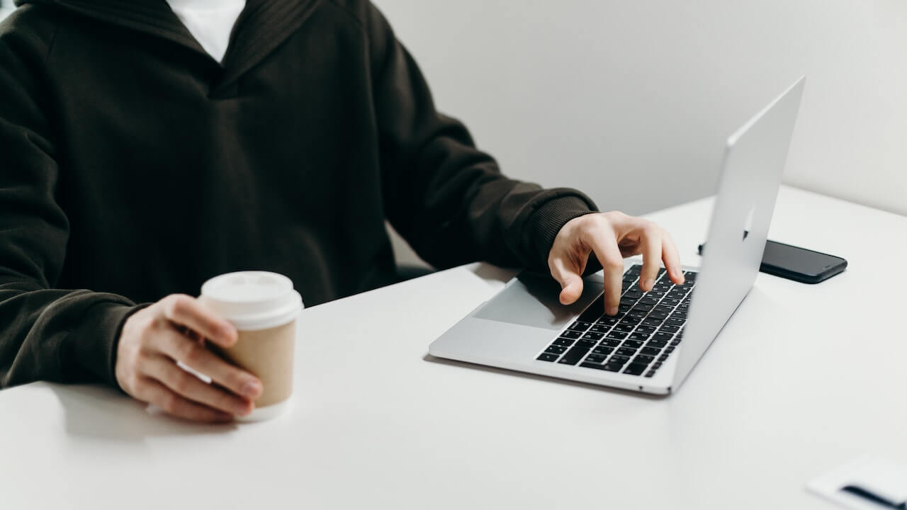 Person in Black Suit Jacket Holding a Coffee Cup